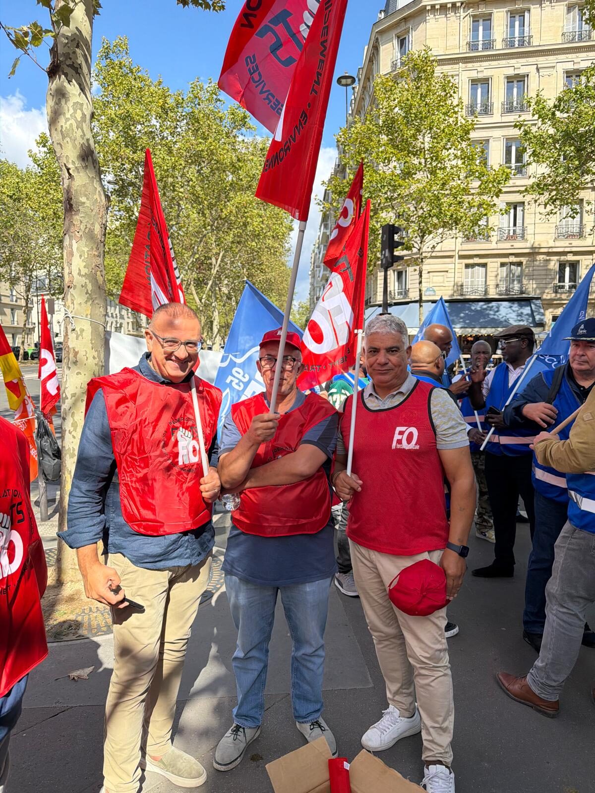 Trois agents en gilet FO, drapeaux CFTC en arrière-plan.