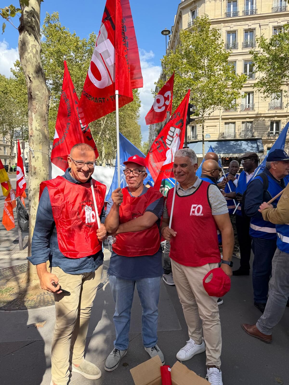 Portrait d'un responsable syndical FO, drapeaux du cortège en arrière-plan.